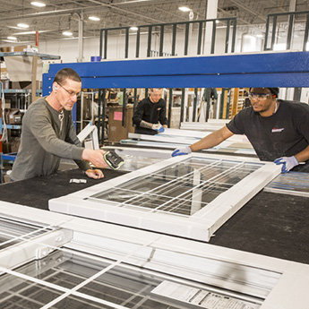 Two employees add a manufacturing code number to a new white vinyl window